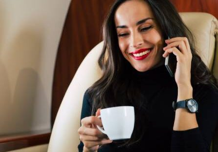 A woman holding a cup while talking on the phone.